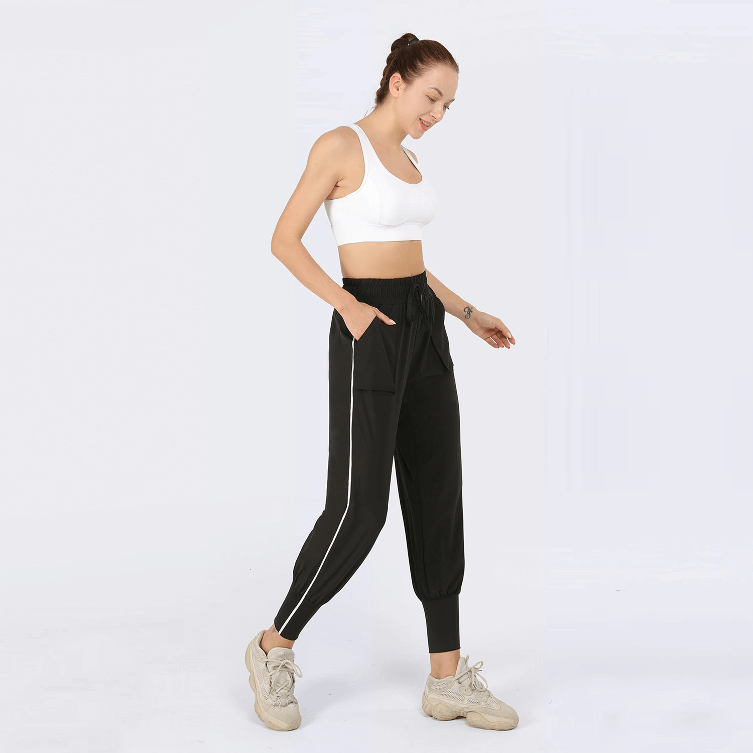 Woman wearing black jogging pants with drawstring waist, paired with white sports top, demonstrating casual activewear style.